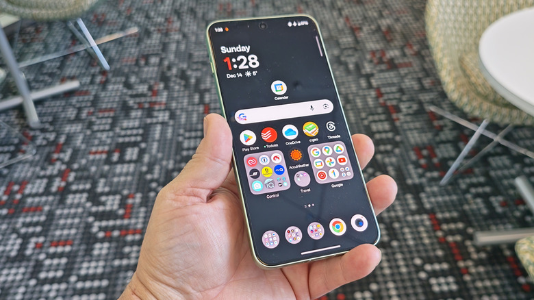 A person holding the OnePlus 15R showing the large 165Hz AMOLED display.