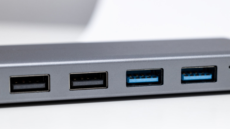 A silver four-port USB hub sitting on a wooden table.