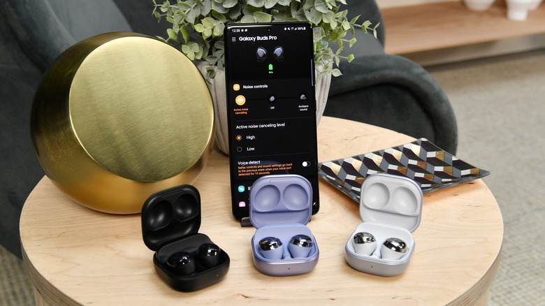 Samsung Galaxy Buds Pro earbuds sitting next to a Galaxy S21 smartphone.