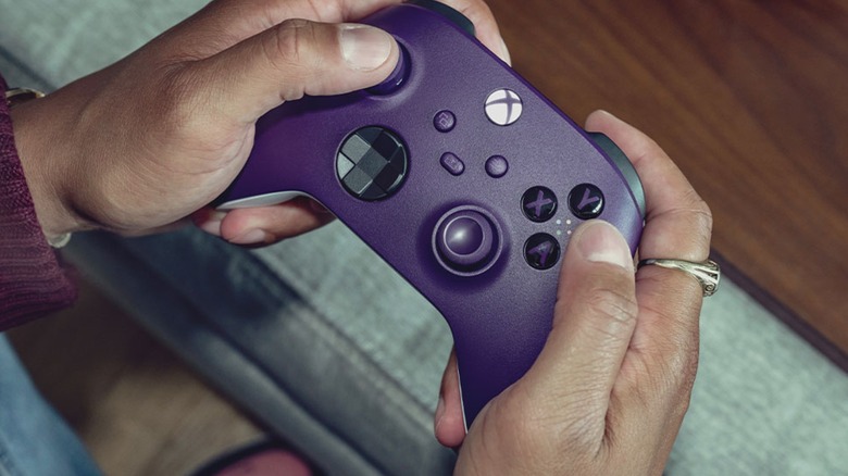 A person holding a purple Xbox Series controller while playing a game