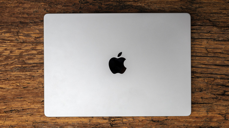 A closed silver MacBook Pro with the Apple logo visible on a wooden background.