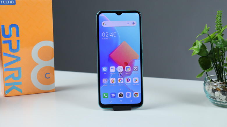A Tecno Spark series smartphone next to its retail box.