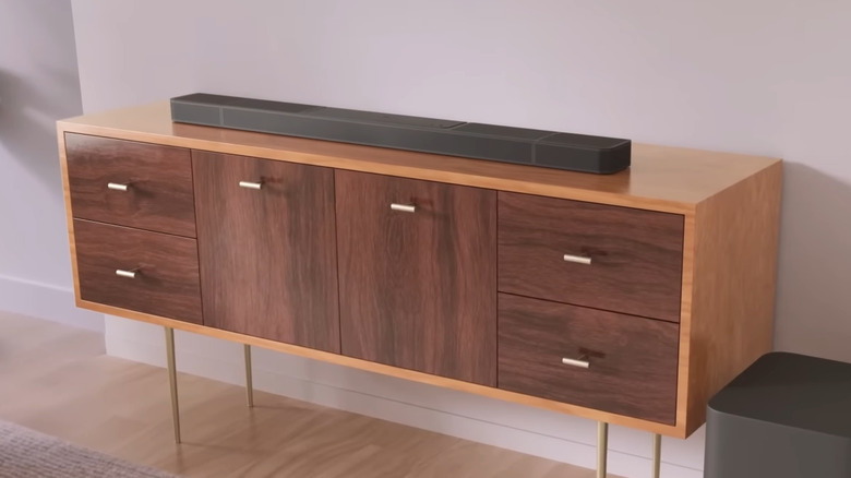 The JBL Bar 1300X soundbar and subwoofer sitting on a wooden media console.