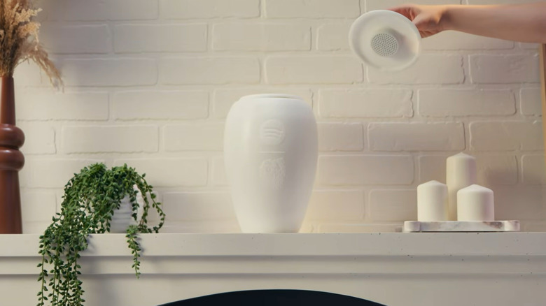 The Eternal Playlist Urn displayed on a white mantel alongside memorial candles and flowers.