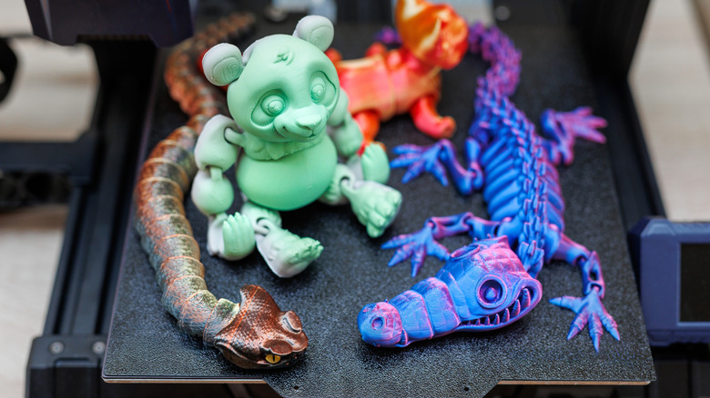 A collection of 3D printed toys sitting on a 3D printer's magnetic build plate.