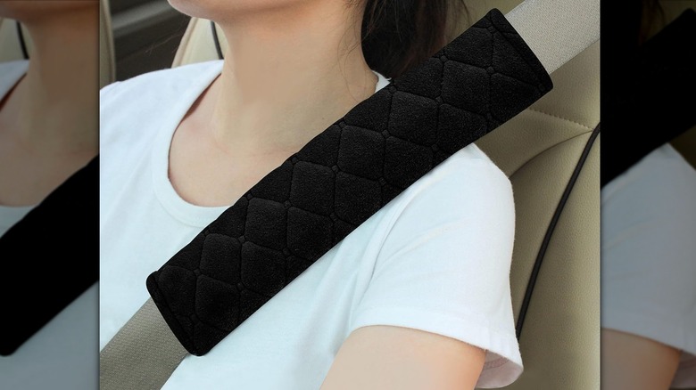 A black Amooca seatbelt cover with a leather-like texture and red stitching.