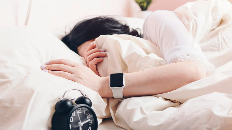 A person lying in bed with an Apple Watch nearby, emphasizing a screen-free morning routine.