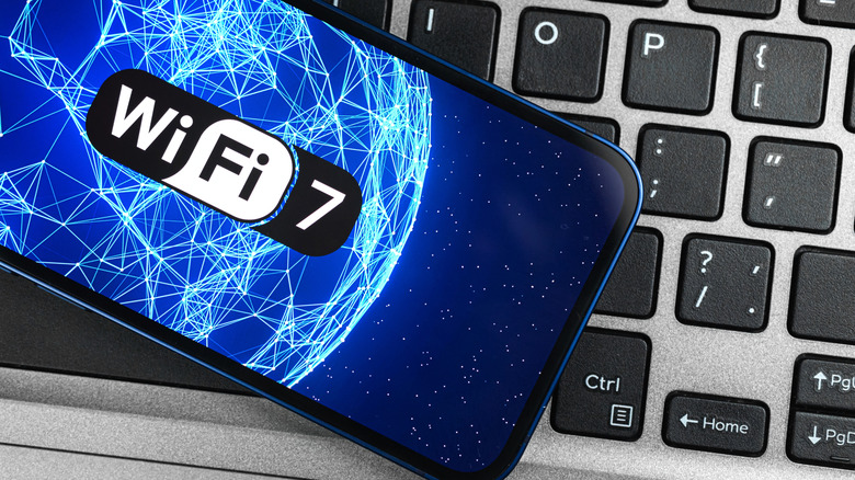 A smartphone showing the Wi-Fi 7 logo resting on a premium laptop keyboard.