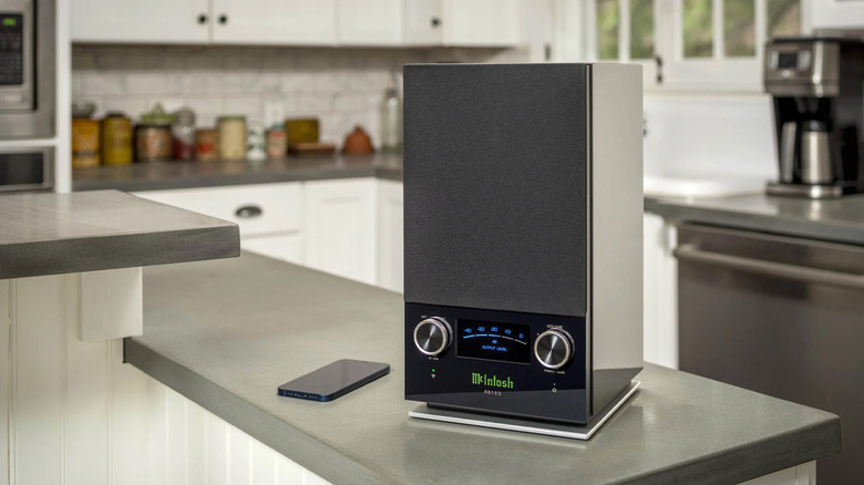 A McIntosh RS150 high-resolution wifi speaker with its signature blue meter on a kitchen bar