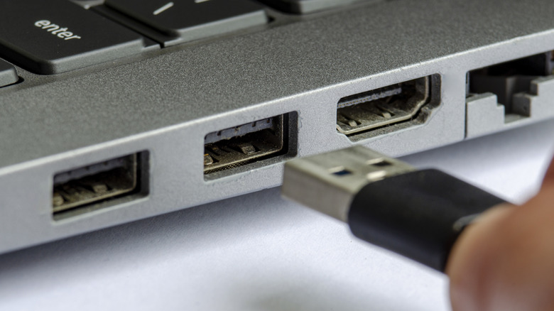 Macro view of a USB Type-A plug approaching a laptop's connection port.