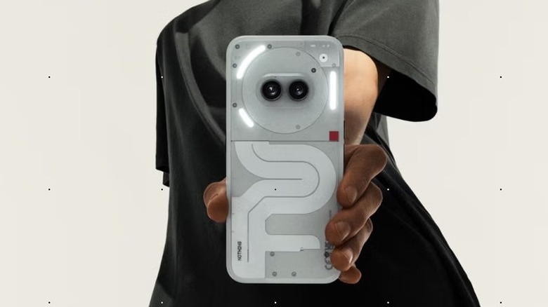 A person's hand holding a white Nothing Phone showing its unique transparent-style rear design.