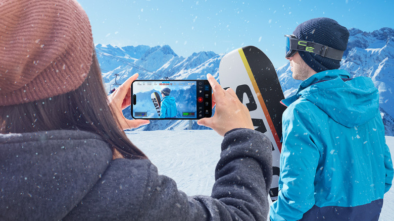 A person using the Blackmagic Camera app interface to record a snowboarder in motion.