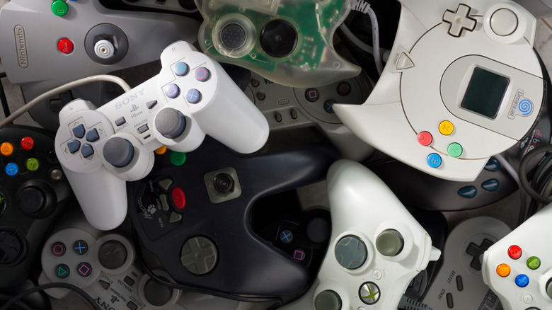 A collection of various retro gaming controllers including a white Xbox 360 controller.