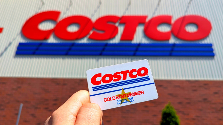 A Costco Gold Star Member card held in front of the warehouse logo.