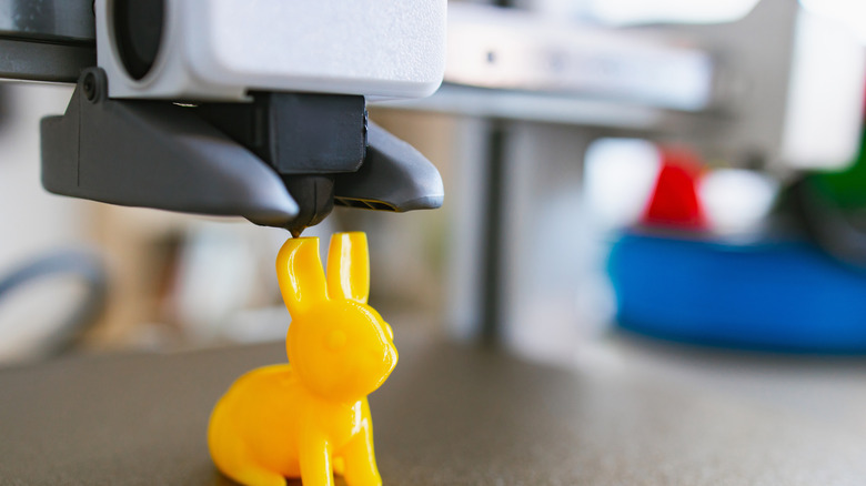 A yellow 3D printed bunny sitting on a printer bed, representing files found on Thangs.