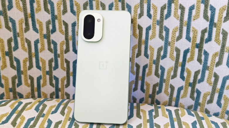 The OnePlus 15R resting on a modern chair to highlight its finish and industrial design.
