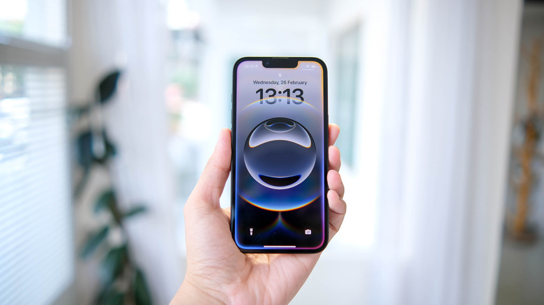 A hand holding a modern iPhone 16e model with a full-screen display and no home button.