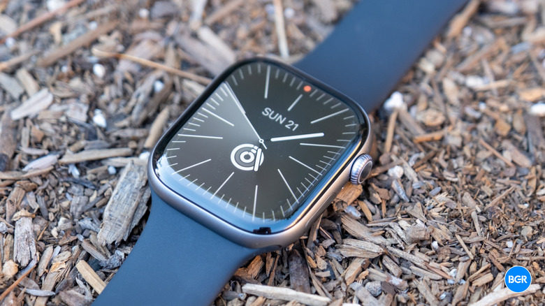 The Apple Watch Series 11 resting on a rough, stony ground surface.