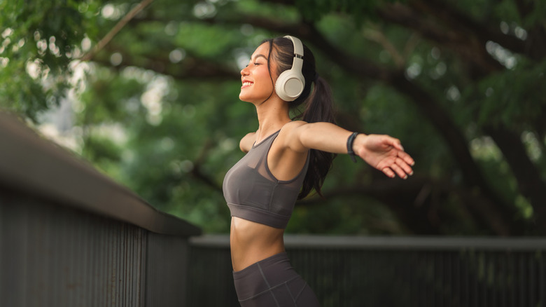 A woman wearing over-ear headphones while exercising outdoors.