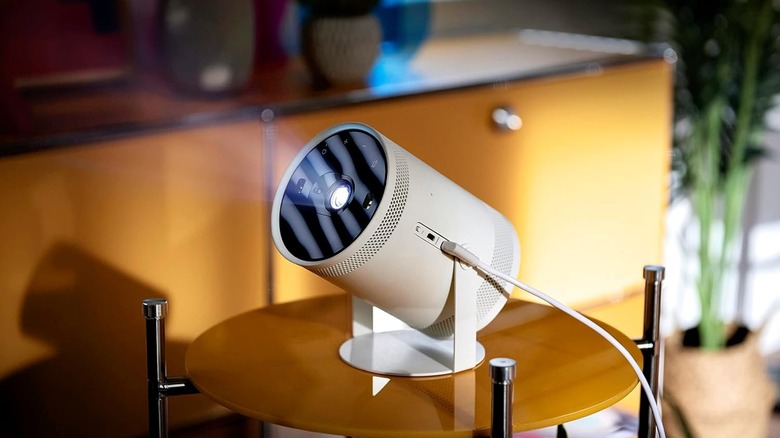 A Samsung The Freestyle projector positioned on a wooden surface for outdoor theater use.