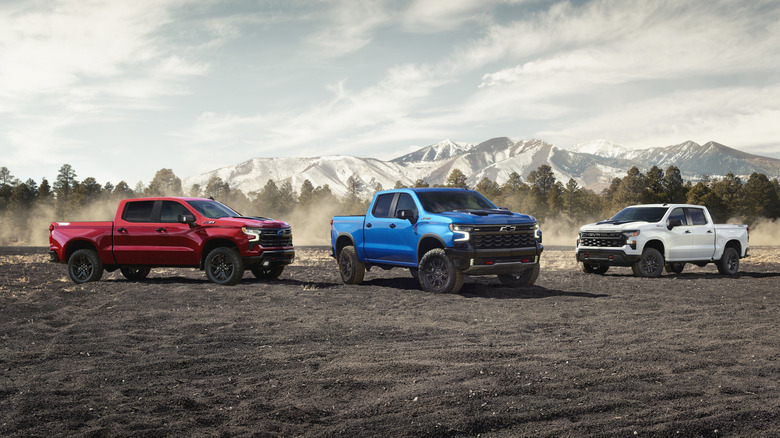 A group of Chevrolet Silverado trucks including LT Trail Boss, ZR2, and Custom Trail Boss trims parked together.