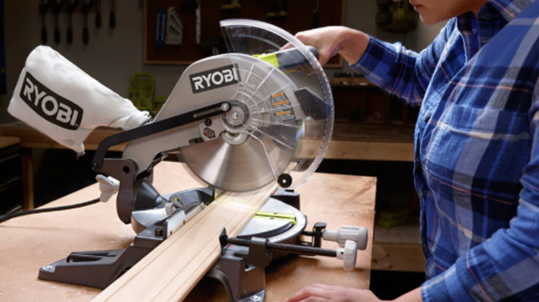 A Ryobi compound miter saw being used for a crosscut.