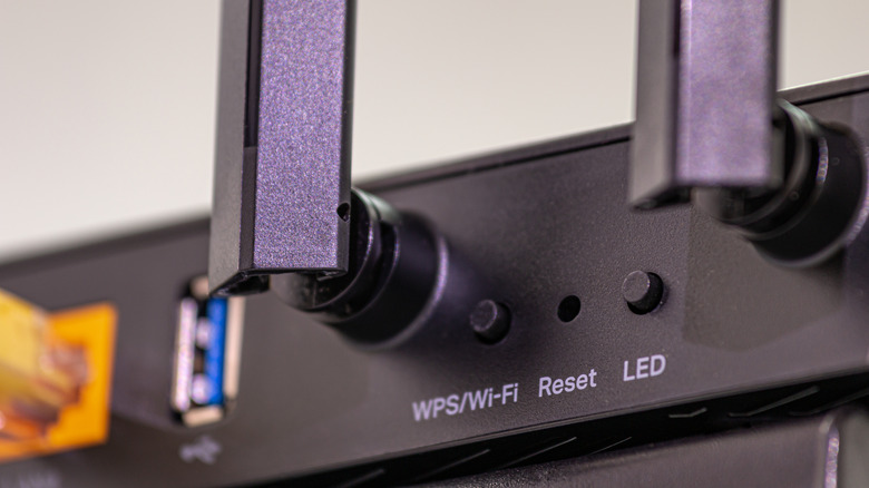 Close-up of a black router showing the WPS button near the Ethernet ports.