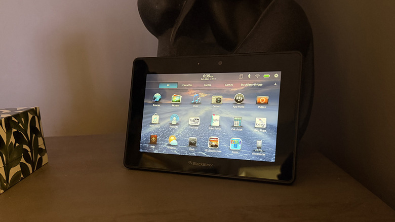 A BlackBerry Playbook tablet leaning against a decorative object on a desk.