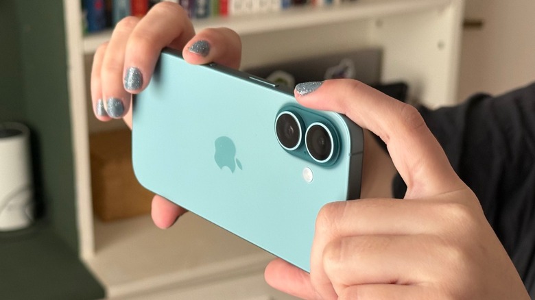 A person using an iPhone 16 to capture a photo, showcasing the Camera Control functionality.