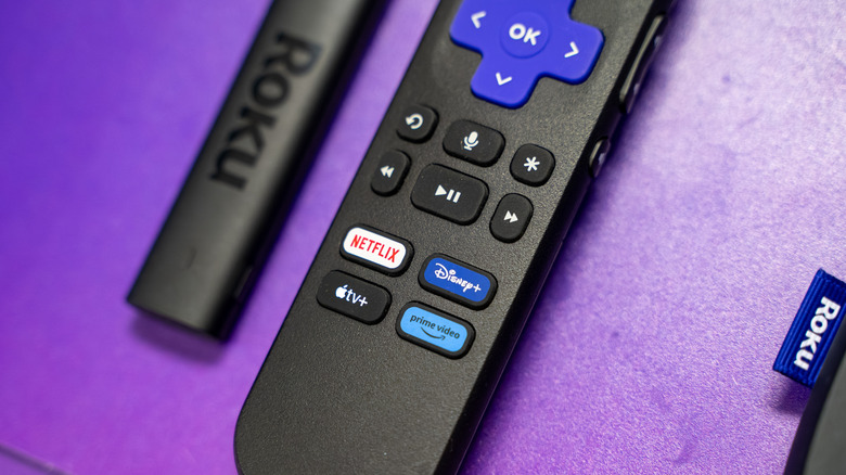 A Roku Streaming Stick 4K lying next to its characteristic purple-button remote.
