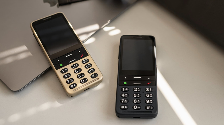 Two BlindShell Classic 3 phones shown in black and gold versions, highlighting their physical keypad.