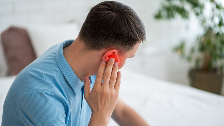 A man experiencing ear pain after cleaning his ears.