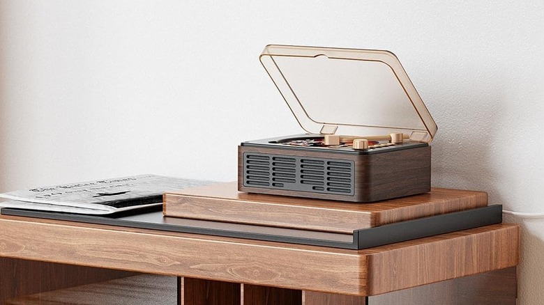 A modern Caronsort CD player with a turntable-style lid on a wooden shelf.