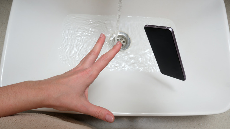 A smartphone being dropped into a water-filled sink