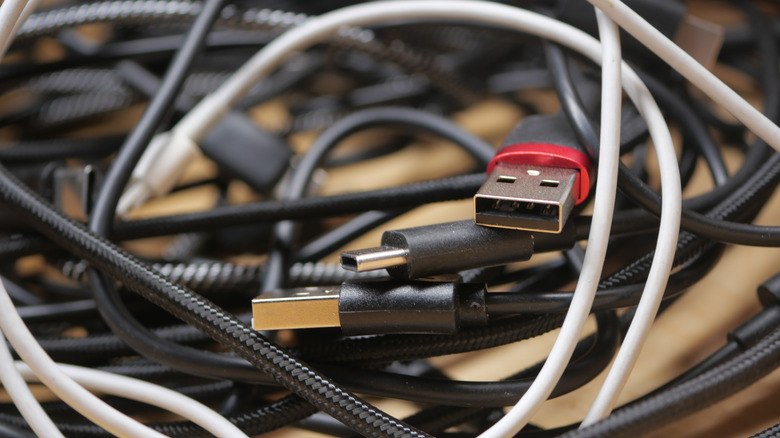 A collection of tangled and messy USB cables lying on a surface.
