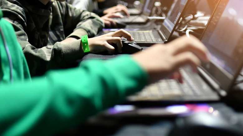 A group of people focused on their laptop screens during a local area network gaming session.