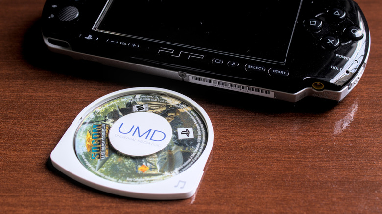 A SOCOM PSP UMD disc next to a black PlayStation Portable console.