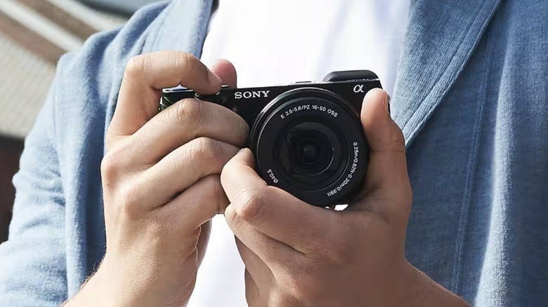 A person holding the compact Sony a6000 mirrorless camera.