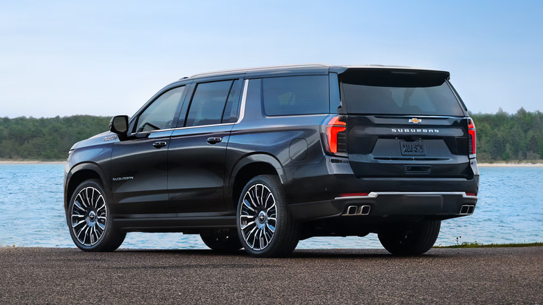 A black 2025 Chevrolet Suburban parked, showing its immense profile from the rear.