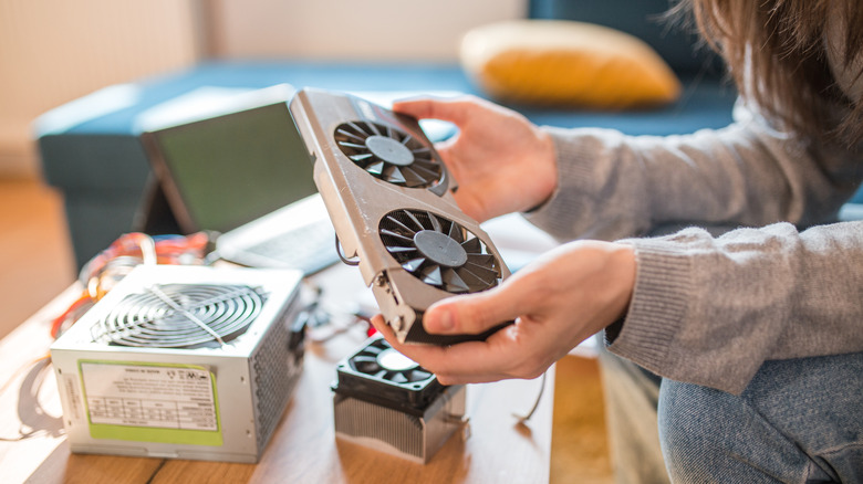 A person holding a compact graphics card while assembling a PC.