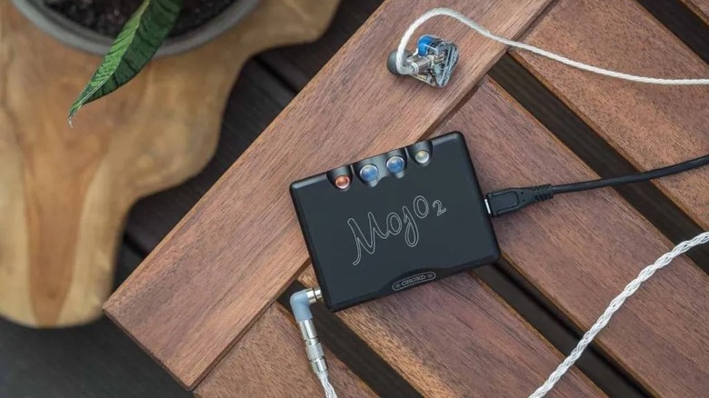 Chord Electronics Mojo 2 portable DAC/Amp on a wooden surface connected to premium IEMs.