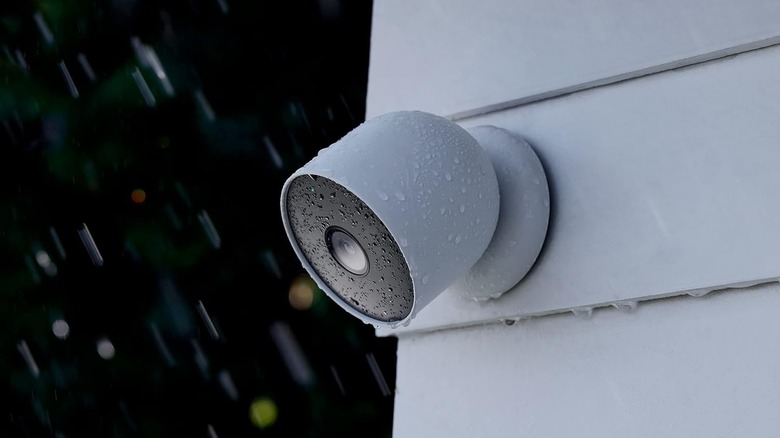 A Nest Cam security camera mounted on a house exterior during rain.