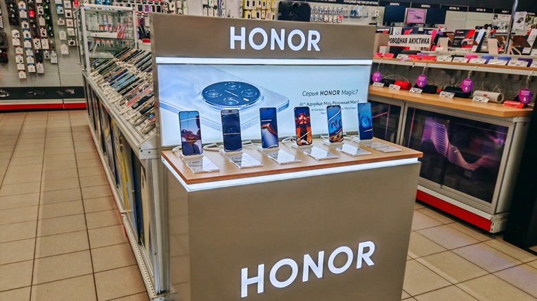 Several Honor smartphones displayed on a wooden table in a brightly lit retail store.