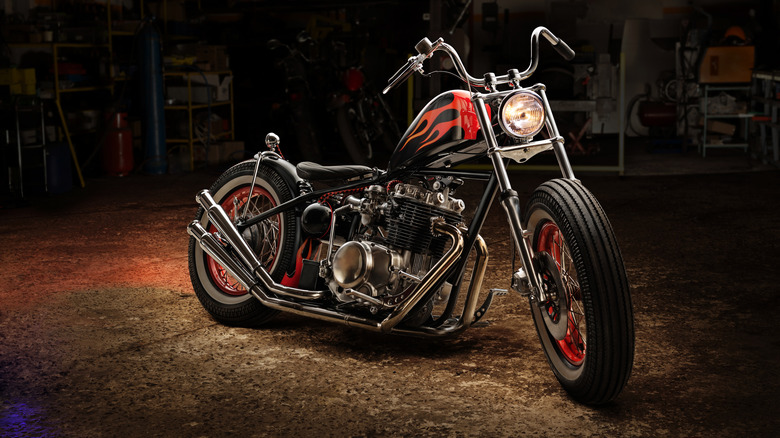A vintage-style custom bobber motorcycle with a chrome engine in a garage.