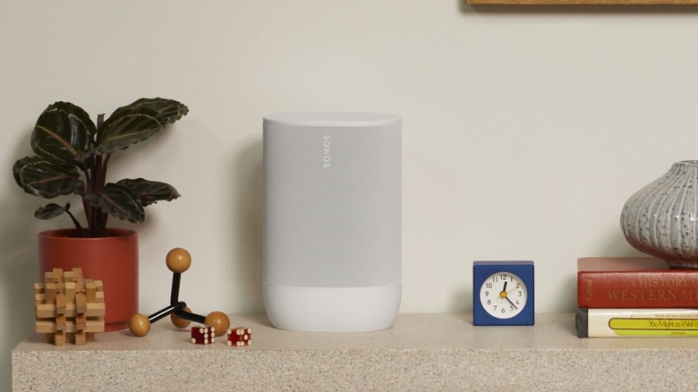 A white Sonos Move 2 speaker sitting on a light-colored wooden shelf.