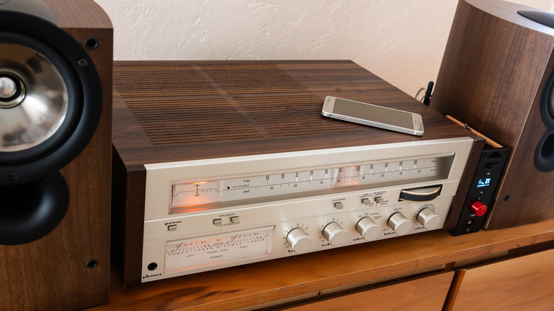 A smartphone sitting on top of a vintage analog stereo receiver.