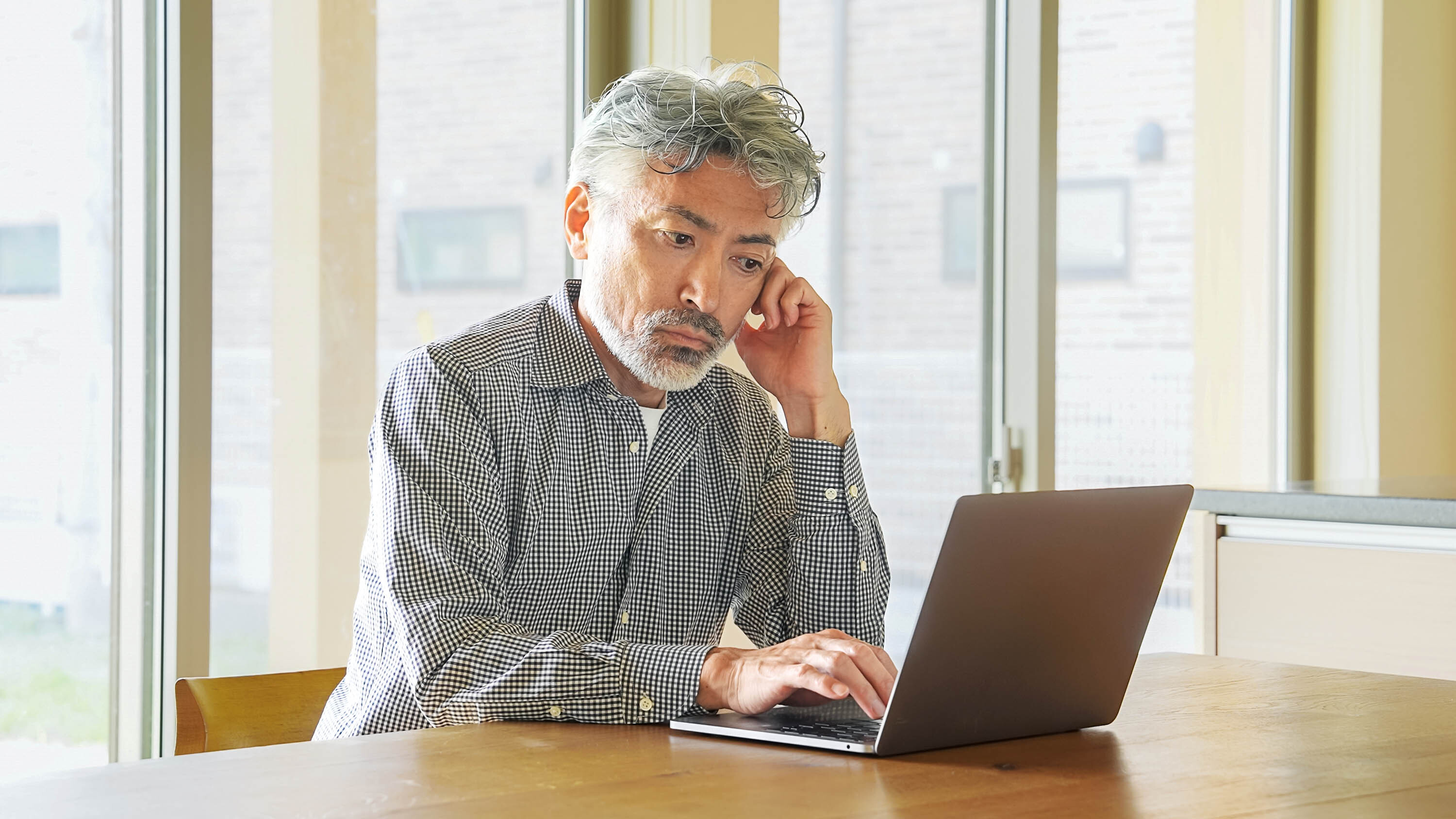 An older man focused intently on a computer screen, representing traditional manual workflows.