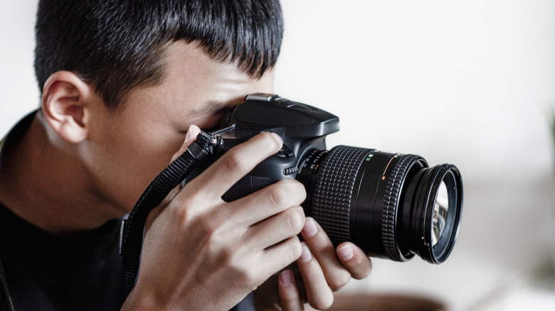 A photographer holding a black DSLR camera ready to take a photo.