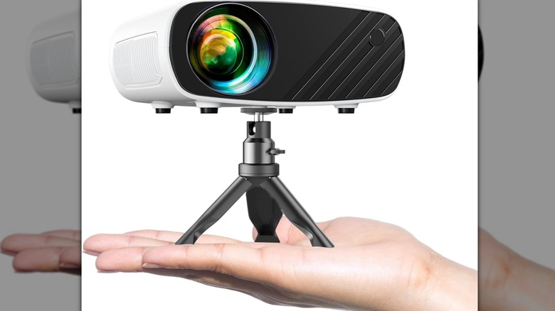 A hand holding up the compact white Elephas mini projector to show its small size.