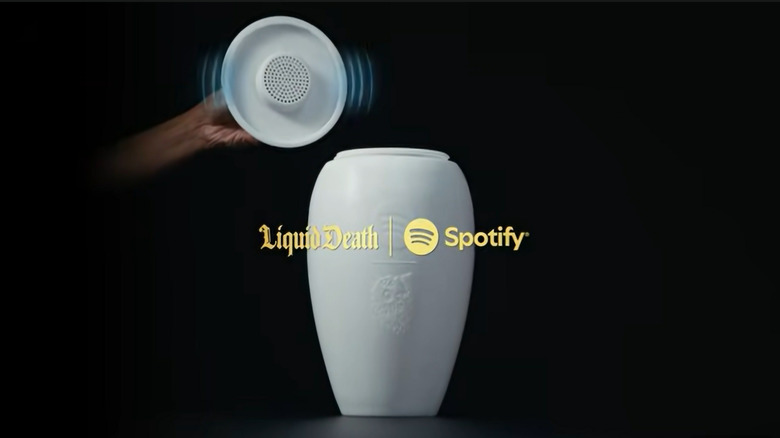Close-up of the Eternal Playlist Urn lid being lifted to reveal an integrated Bluetooth speaker with digital sound wave graphics.
